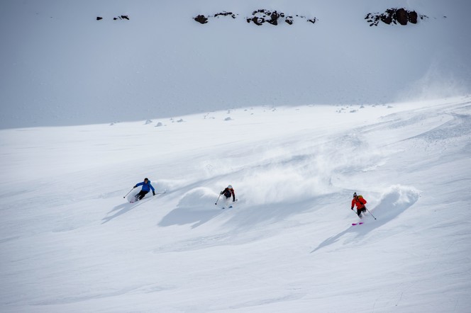 Three skiers headed down a powdery mountain in Iceland.